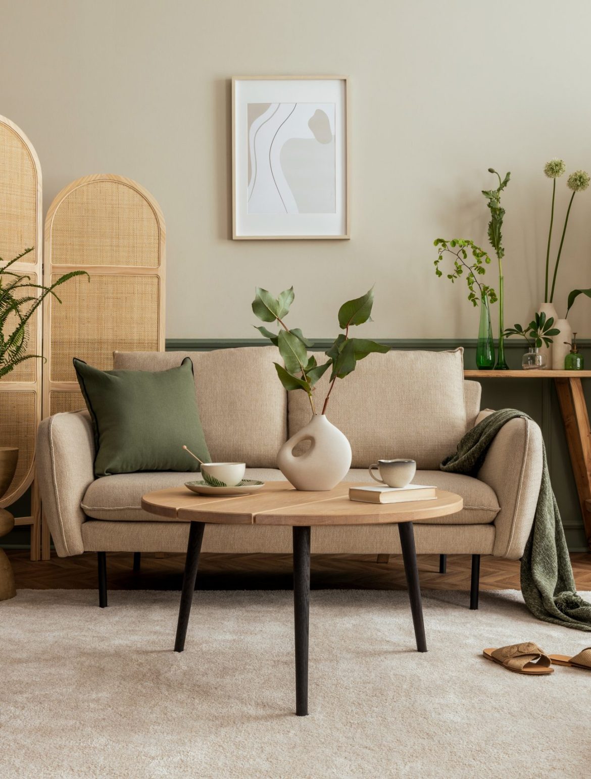 Creative composition of living room interior with beige sofa, wooden coffee table, rattan sideboard, partition wall, lamp, beige carpet, stylish armchair and personal accessories. Home decor. Template.