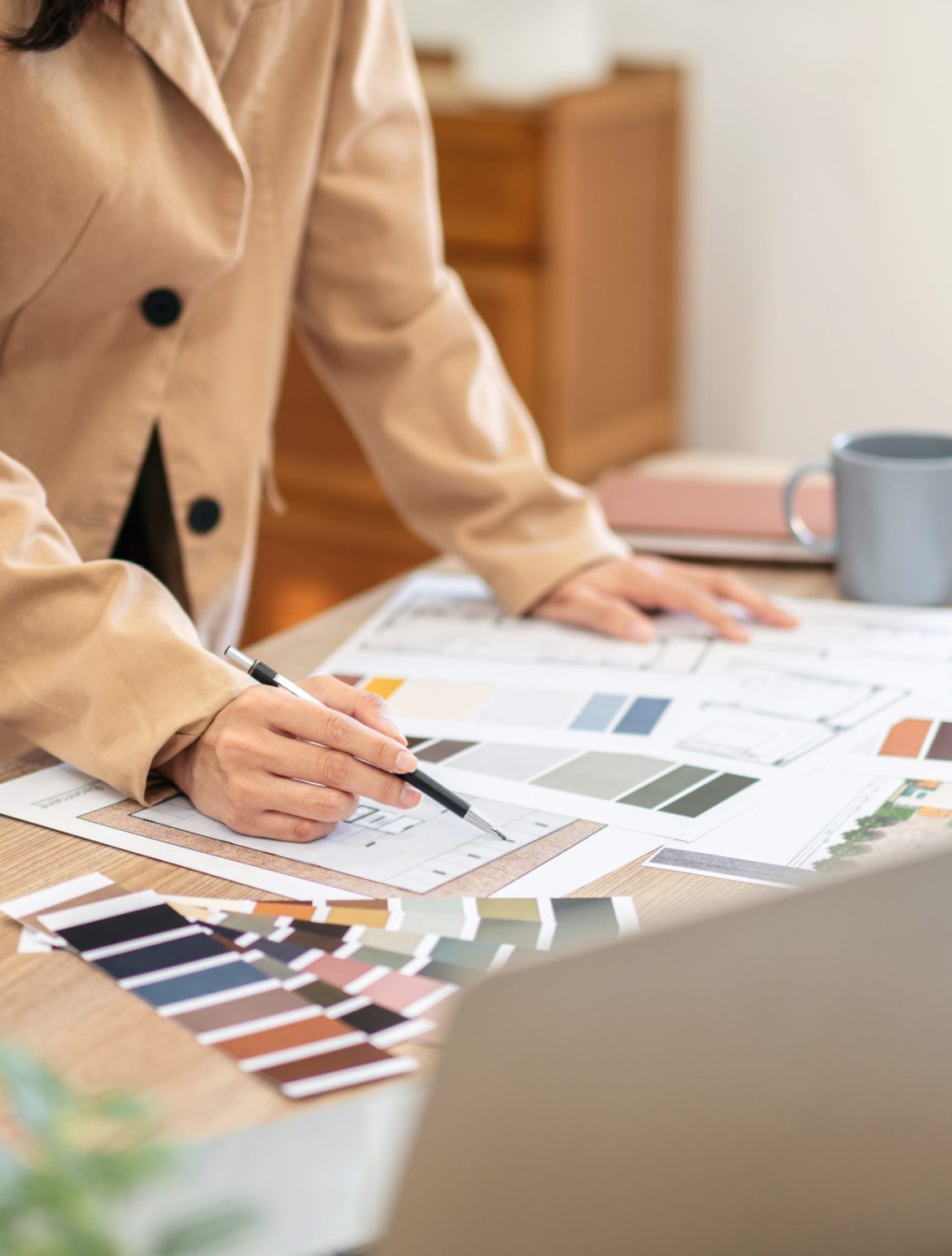 Woman architect working to sketching and designing building on blueprint while work about planning construction project on laptop in modern office.